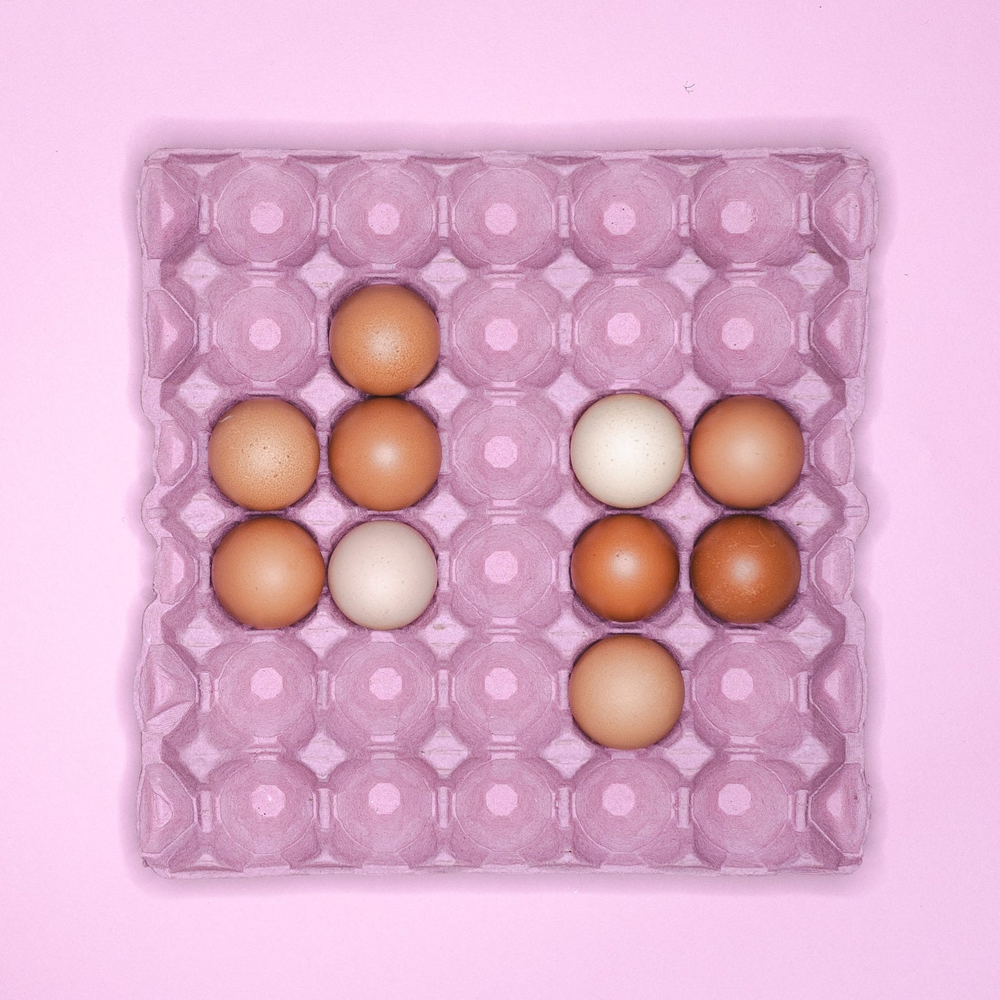 A pink cardboard tray holding 10 eggs