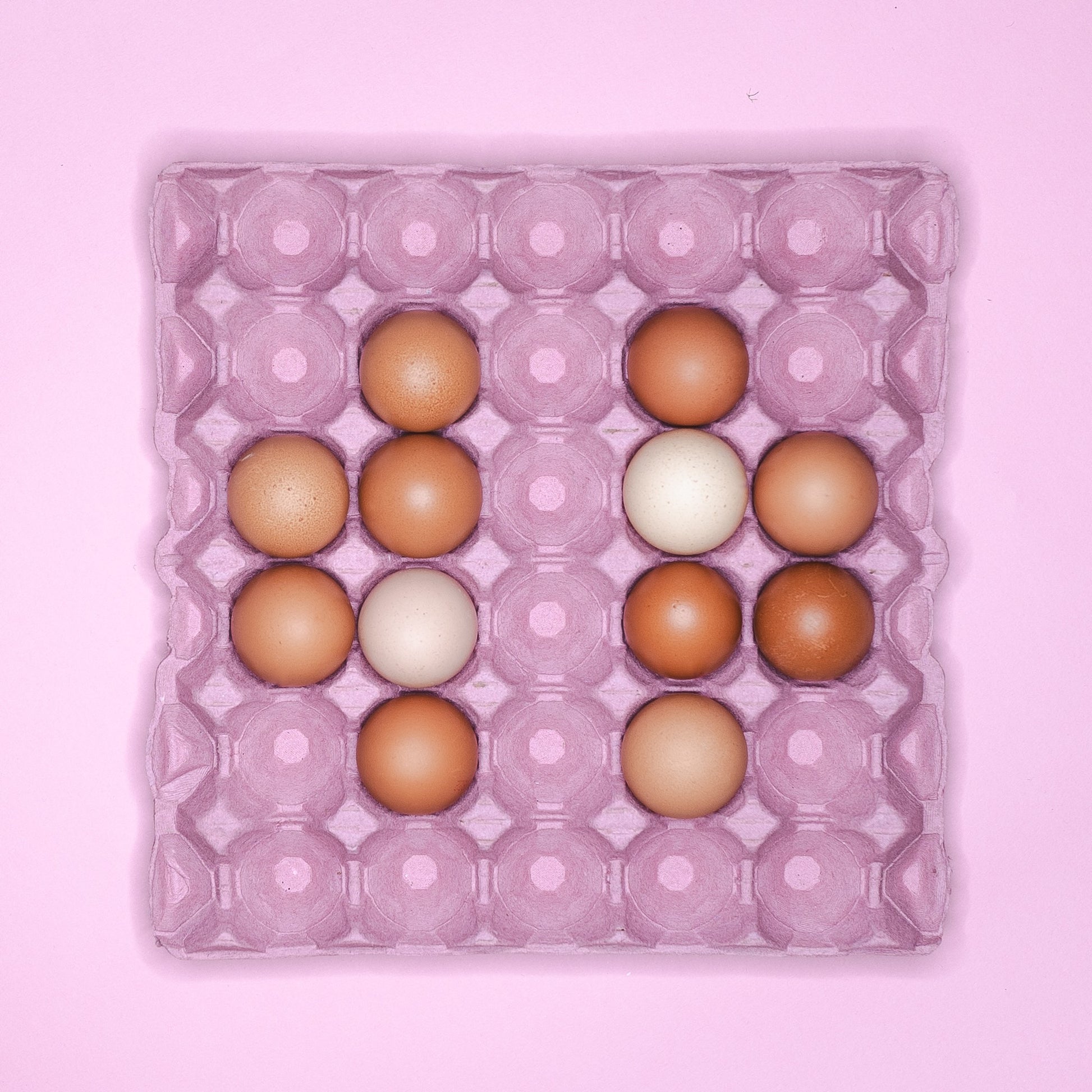 A pink cardboard tray holding 12 eggs