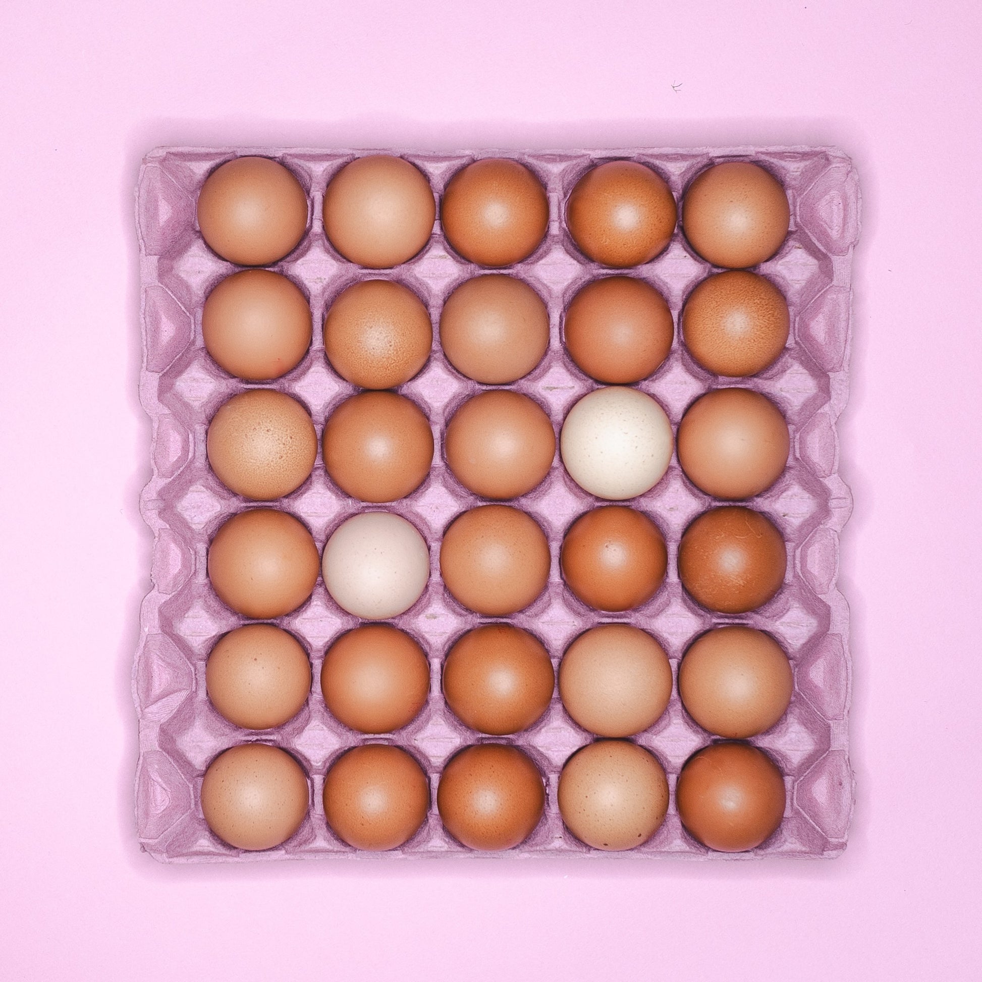 A pink cardboard tray holding 30 eggs